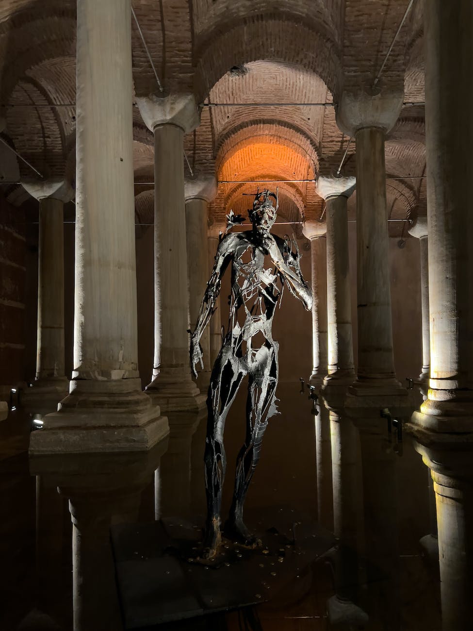 spooky metal sculpture in a cistern interior with arches and columns