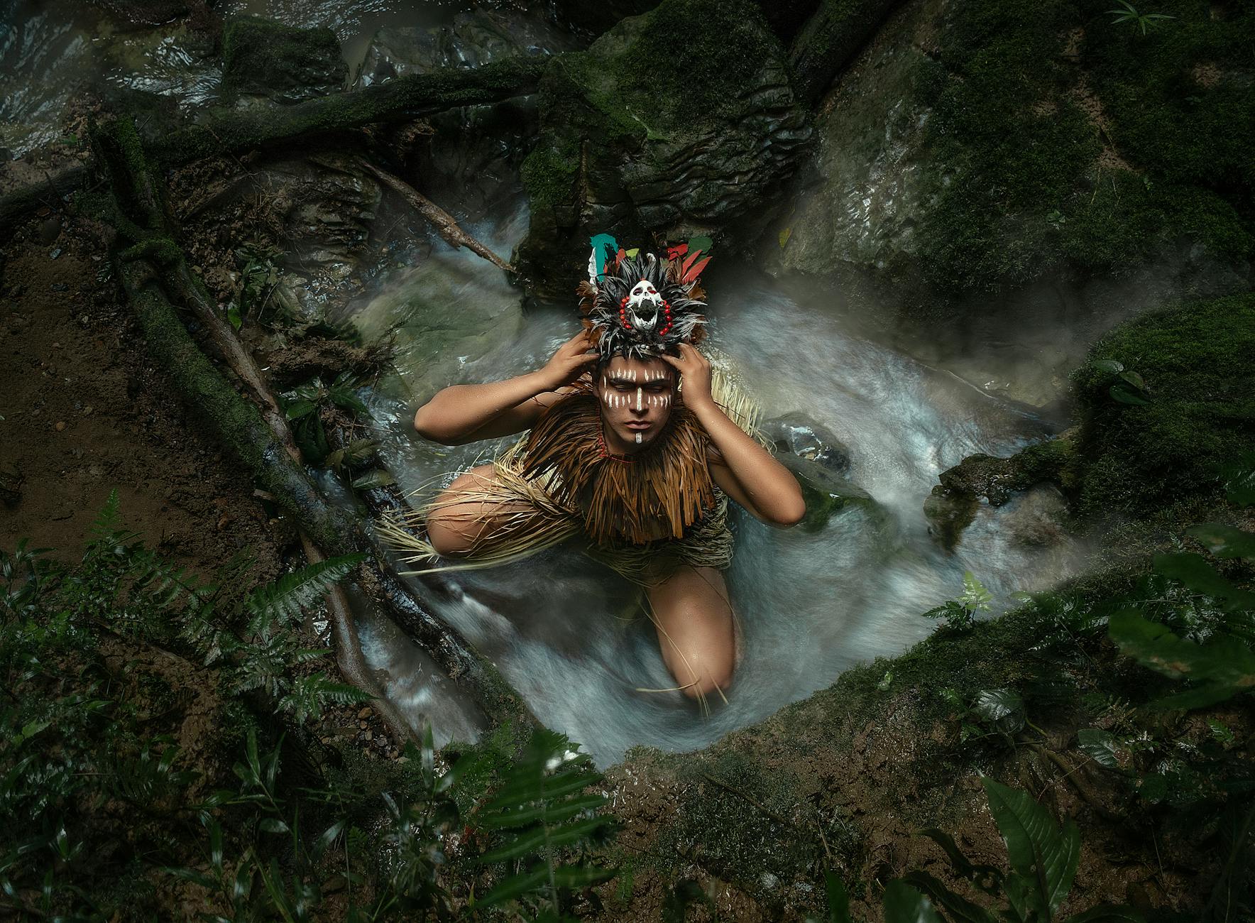 person sitting and posing in traditional native american clothing